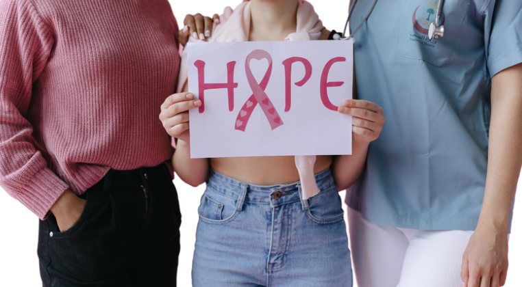 Three young women holding a HOPE sign with a pink ribbon